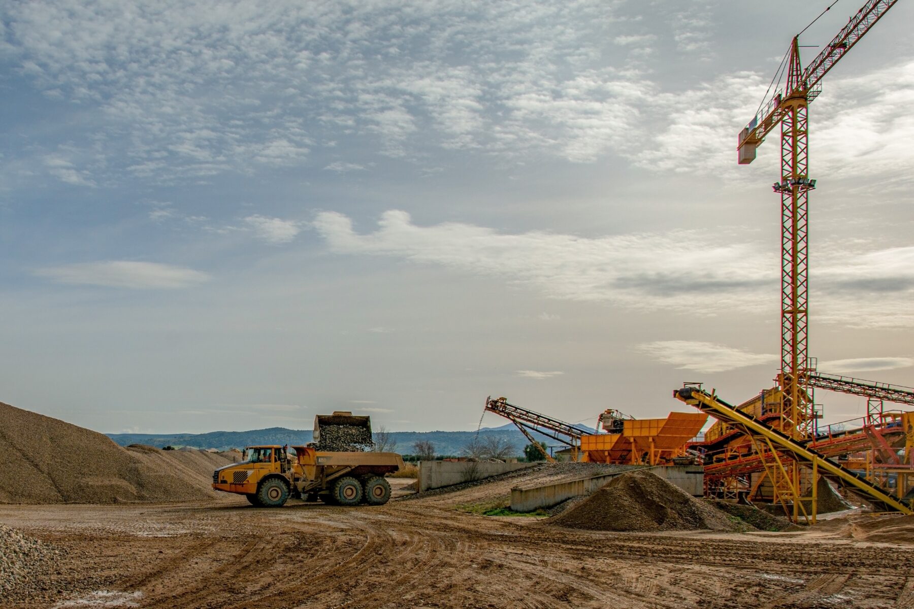 Construction aggregate quarry with stockpiled stone, conveyors, and hauling equipment that highlights the importance of quarry processing and quality control in overall project performance.